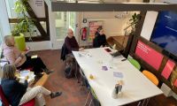 Menschen sitzen bei einer Veranstaltung im stadtLABOR und schauen auf den Bildschirm