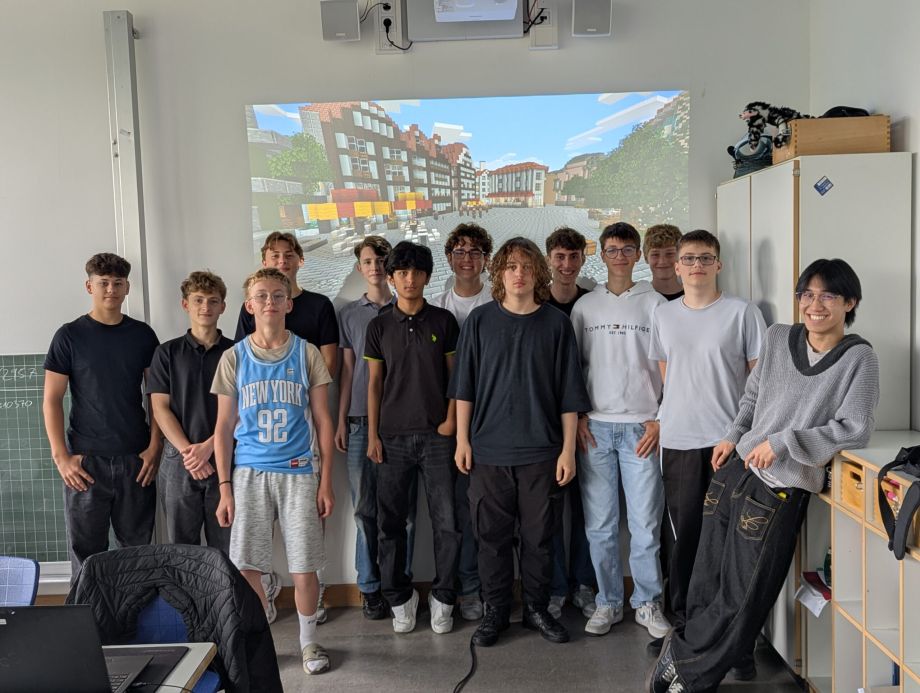 Das Bild zeigt eine Gruppe von Schülern, die stolz vor der Präsentation ihrer Minecraft-Bauwerke stehen.