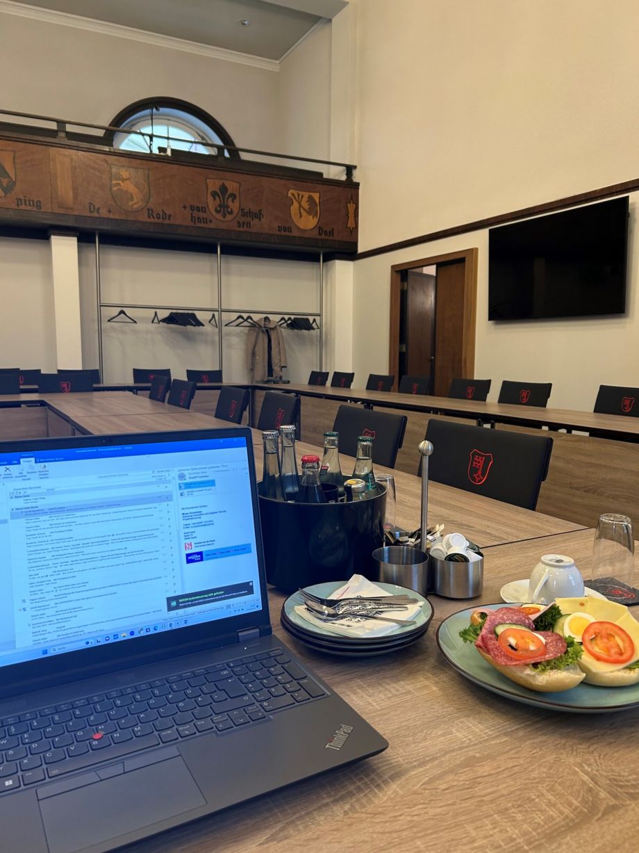 Das Bild zeigt im Vordergrund einen Laptop im Ratssaal des Rathauses Soest.