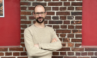 Porträtfoto von Richard Nüsken, der an einer Backsteinwand lehnt.