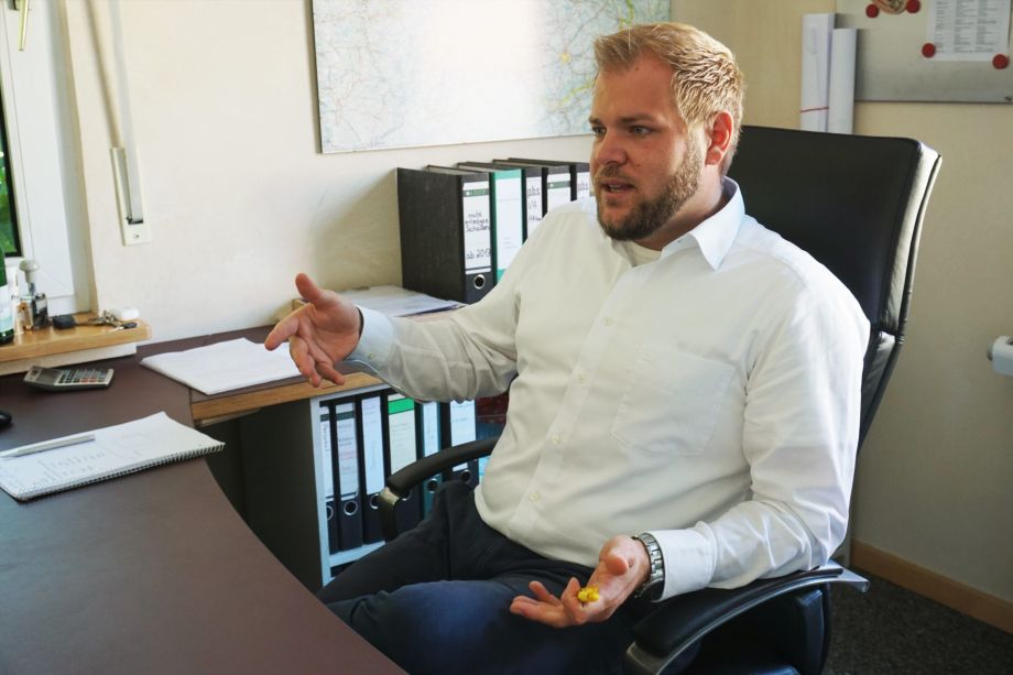 Porträtfoto von Lukas Brüggemann, der gestikulierend am Schreibtisch sitzt.