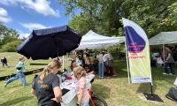 Schools Out Day im Stadtpark Soest. Kinder stehen um ein Lastenrad herum und malen, im Hintergrund spielen Kinder an Laptops Minecraft.