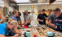 Eine Gruppe Imkerinnen und Imker aus Soest und Umgebung, die gemeinsam in der Holzwerkstatt digitale Bienenstöcke bauen.