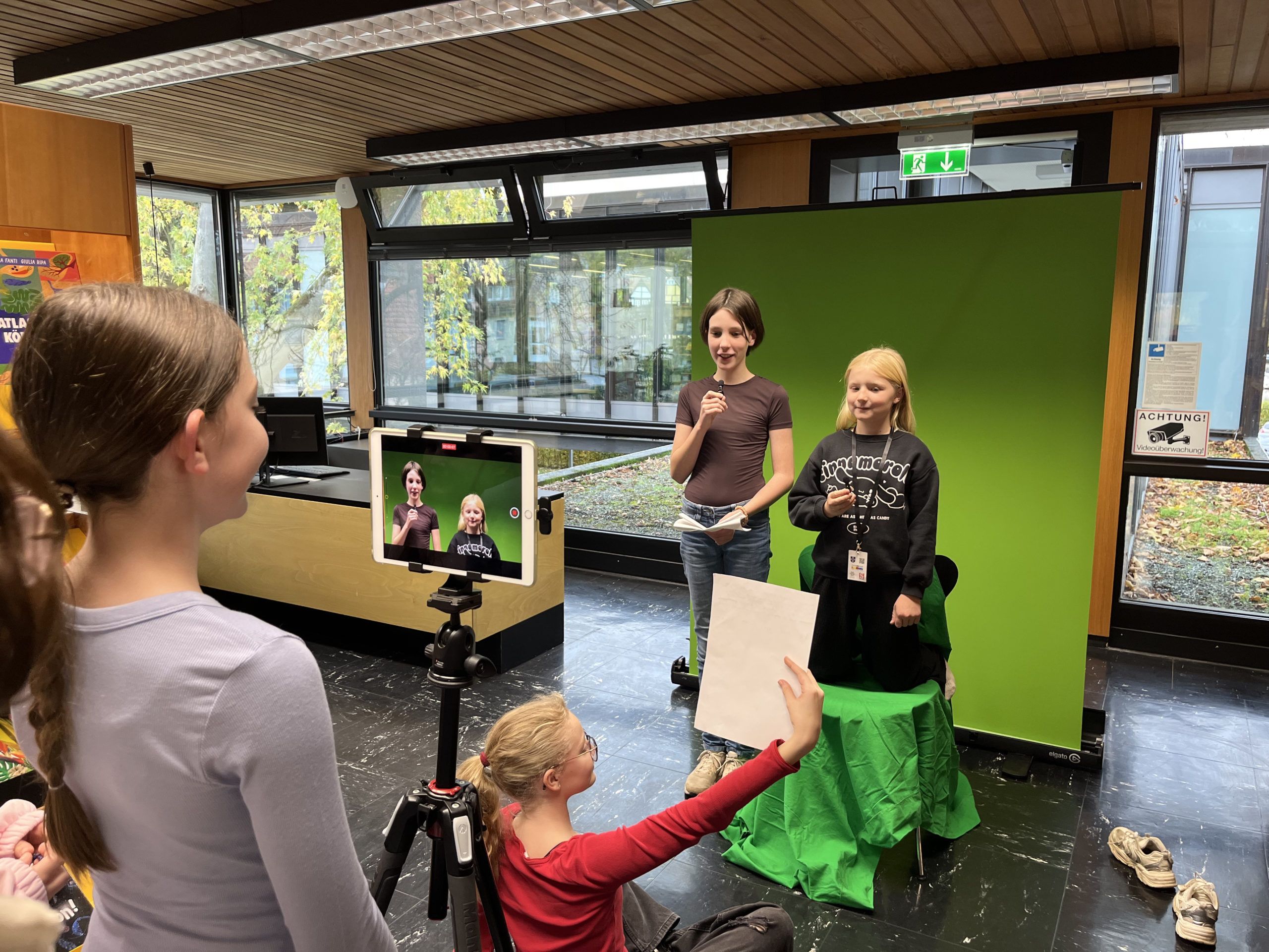 Kinder vor einem Greenscreen hinter einer Kamera