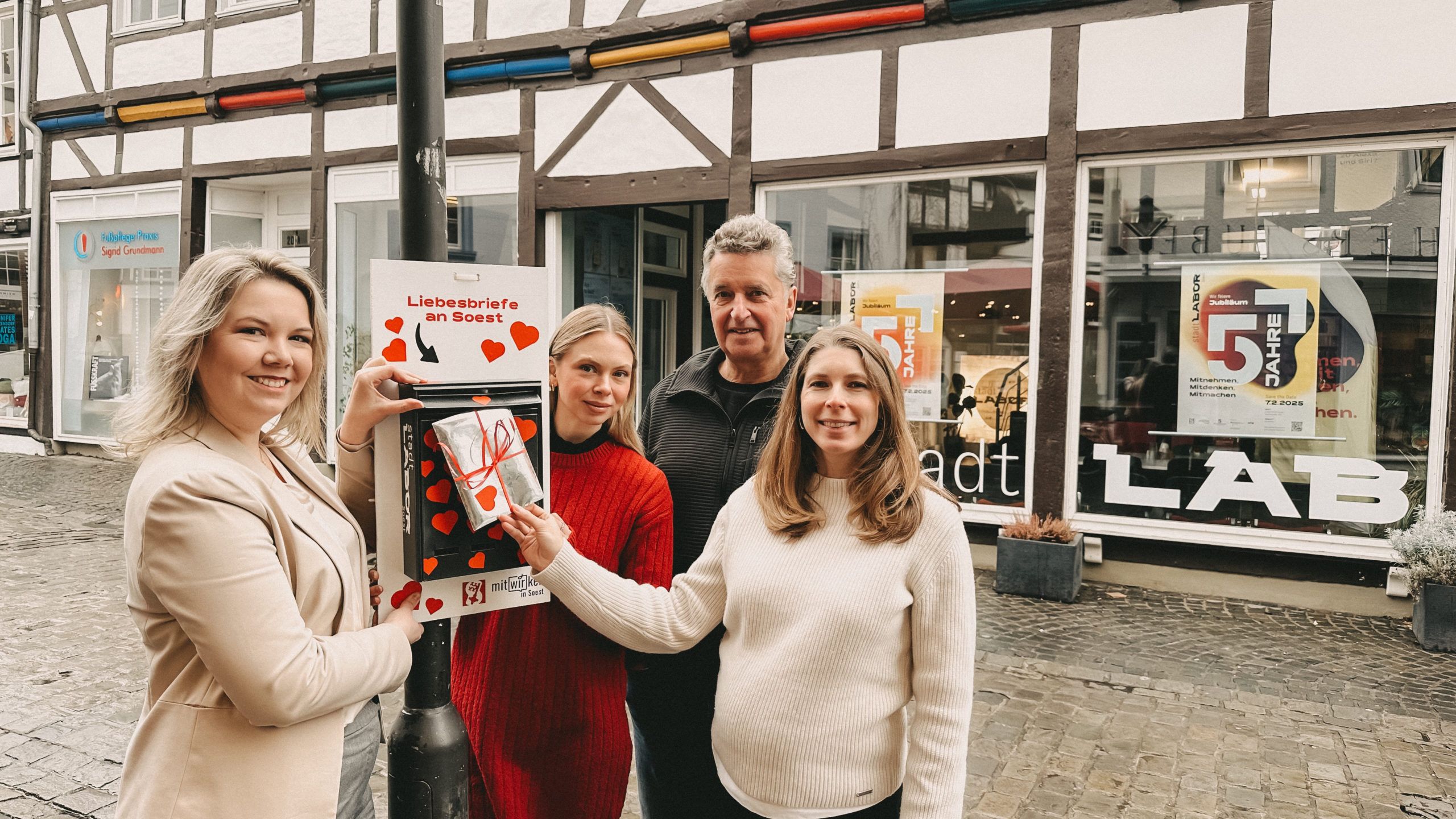 Team vom stadtLABOR, WMS, Stadt Soest und Schönes Soest stehen vor dem stadtLABOR und werfen einen Brief in den Liebesbriefkasten ein.