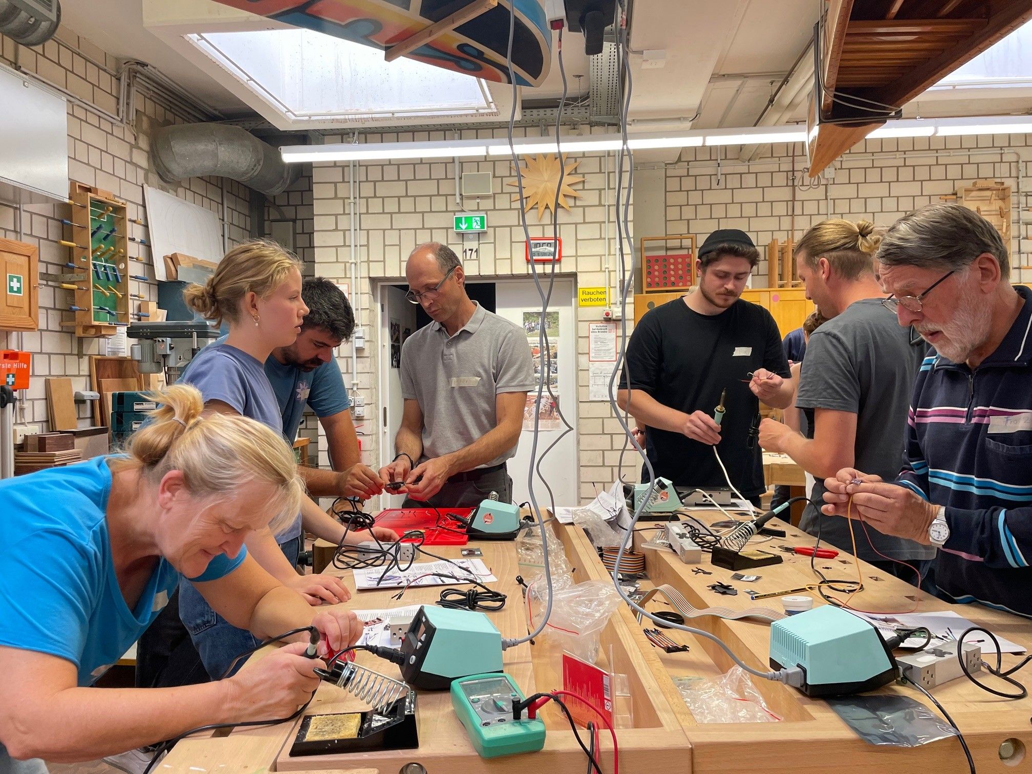 Eine Gruppe Imkerinnen und Imker aus Soest und Umgebung, die gemeinsam in der Holzwerkstatt digitale Bienenstöcke bauen.