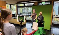 Kinder vor einem Greenscreen hinter einer Kamera