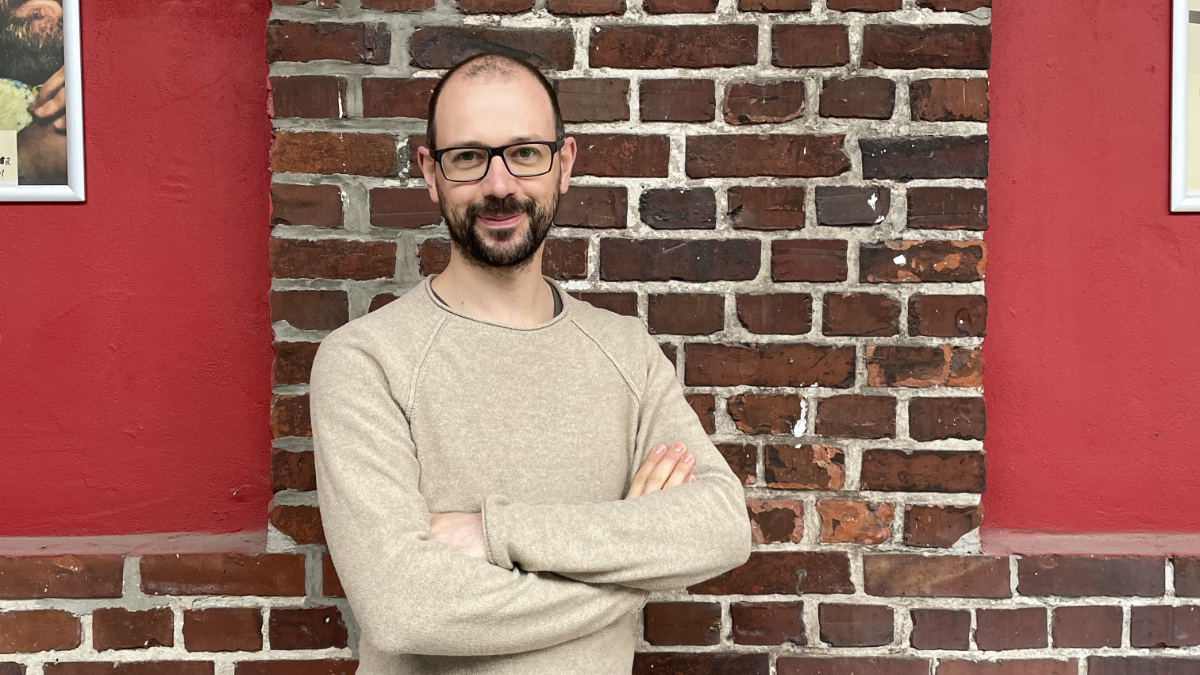 Porträtfoto von Richard Nüsken, der an einer Backsteinwand lehnt.