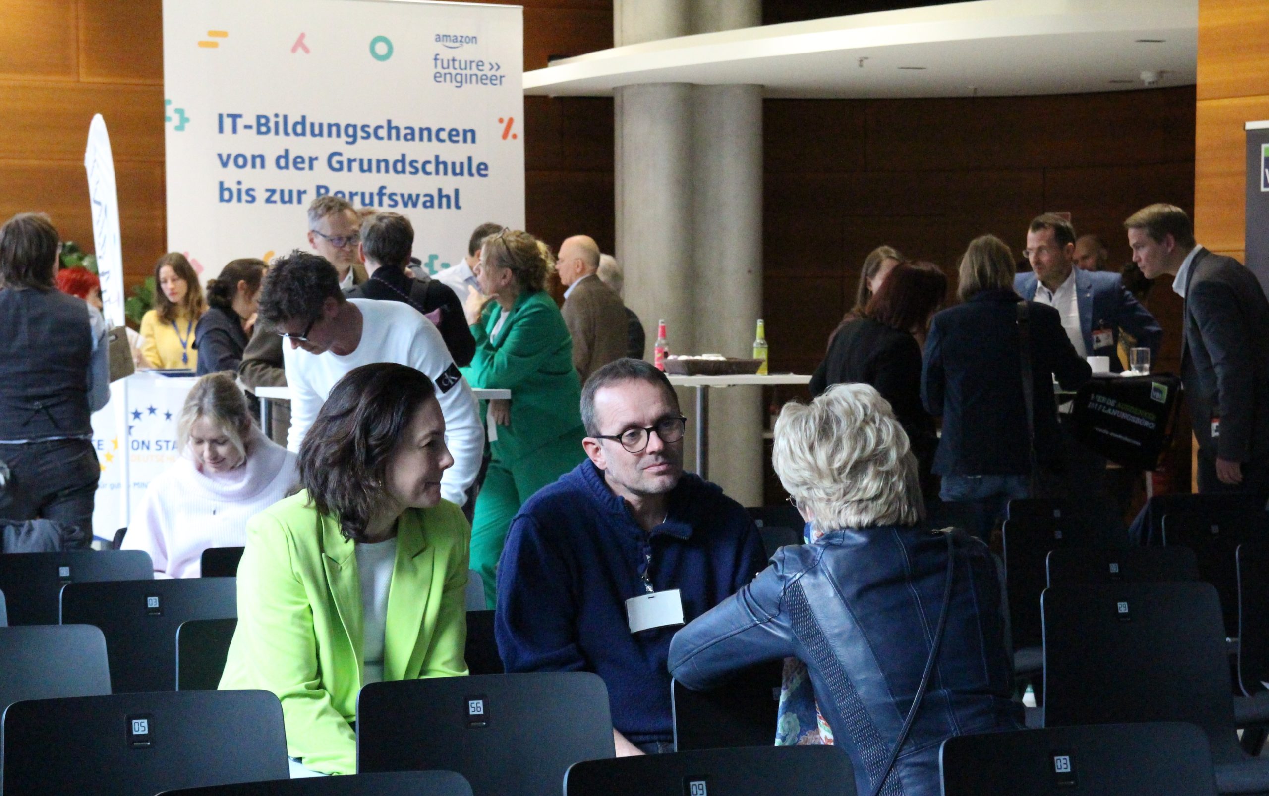 Menschen unterhalten sich an einem Tisch. Im Hintergrund sind weitere Personen zu sehen, die in Gespräche vertieft sind.