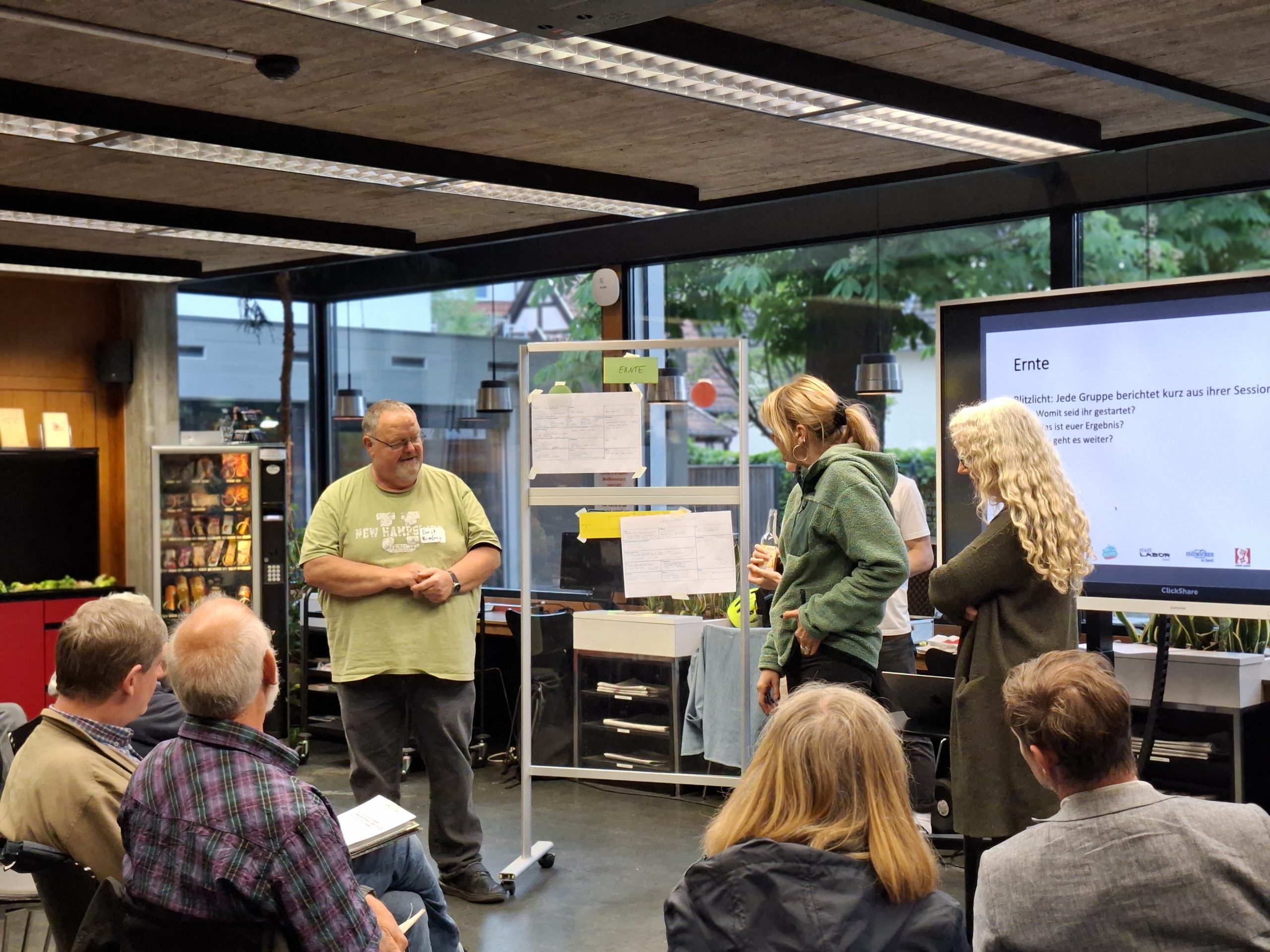 Menschen sitzen bei der Veranstaltung Klimaforum und hören einer Gruppe zu, die vorne steht und etwas präsentiert.