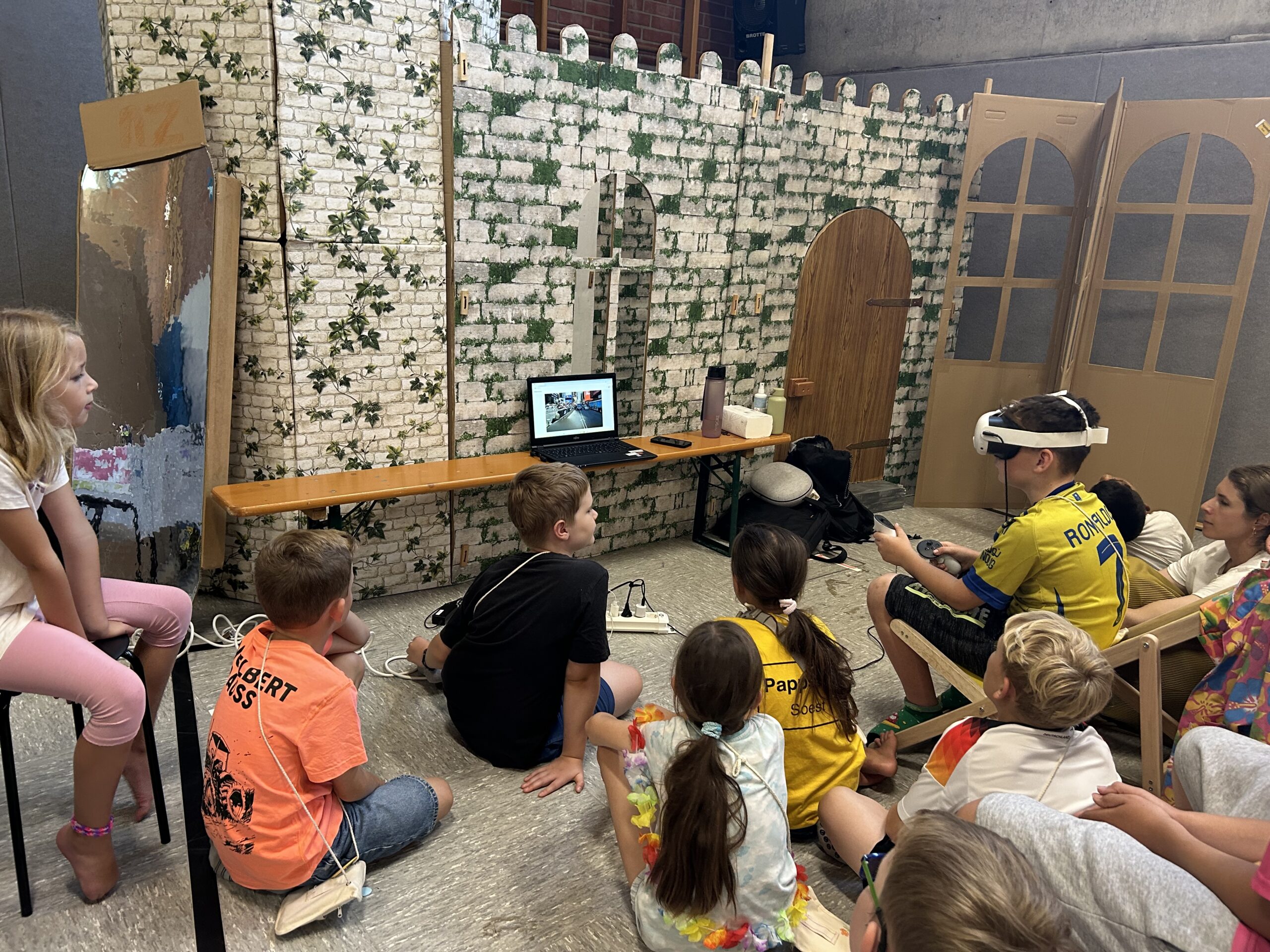 Kinder schauen einem Kind zu der eine VR-Brille trägt