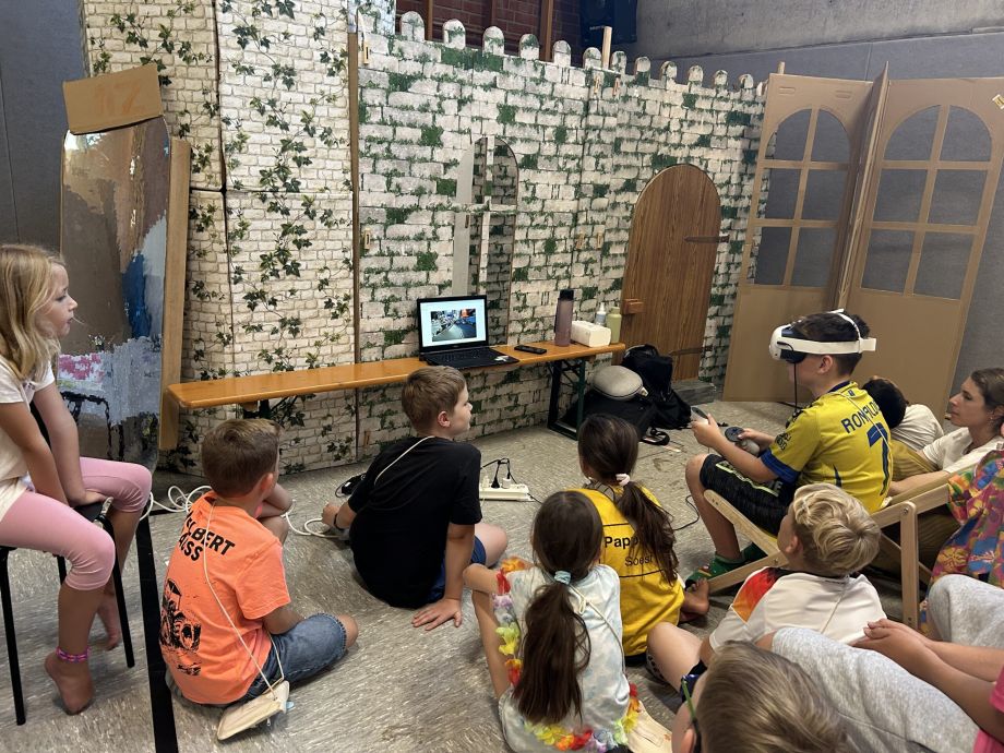 Kinder schauen einem Kind zu der eine VR-Brille trägt