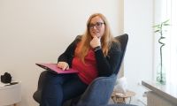 Porträtfoto von Simone Folke, die in einem Sessel sitzt.