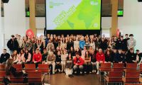 Ein Gruppenbild von einer Schulgruppe, im Hintergrund ist eine große Leinwand zu sehen mit dem Logo des Young Climathon