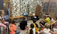 Kinder schauen einem Kind zu der eine VR-Brille trägt